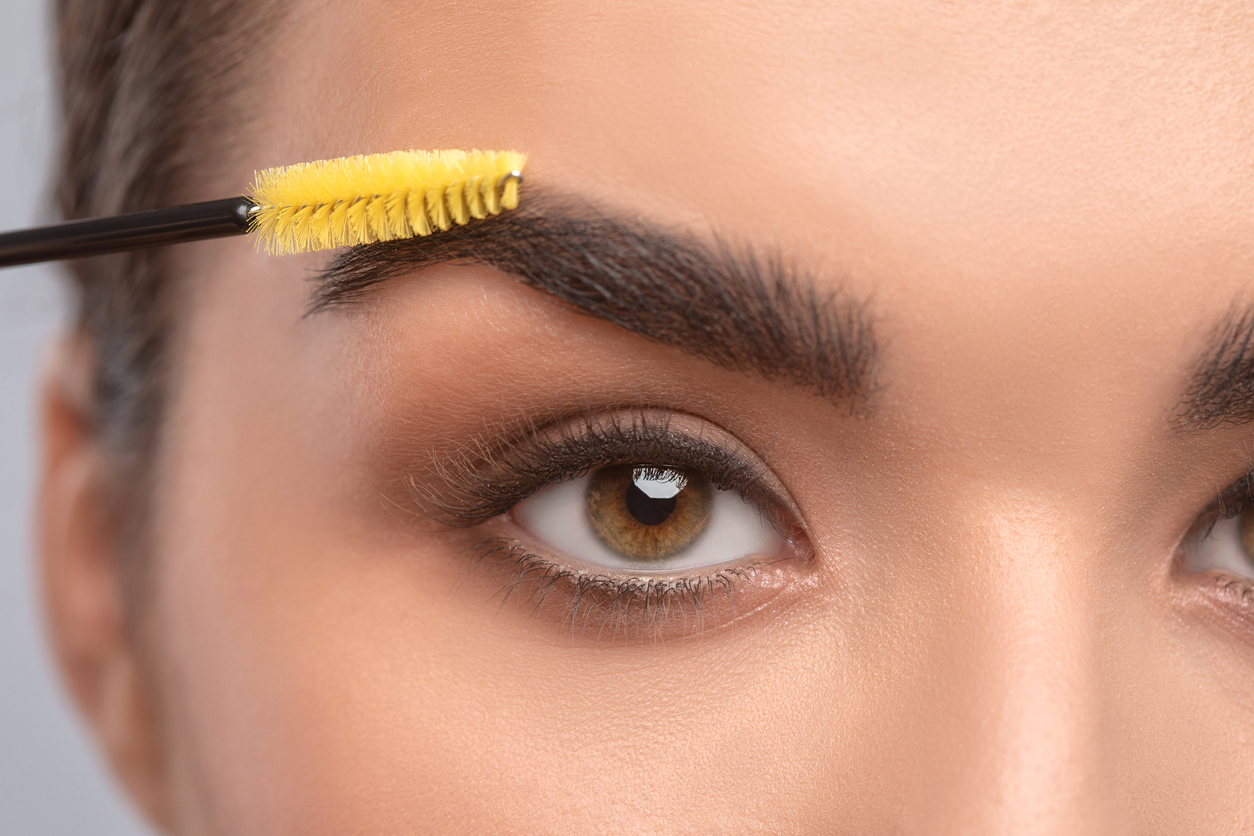 Makeup artist combs eyebrows with a brush after dyeing in a beauty salon.Professional makeup and cosmetology skin care.